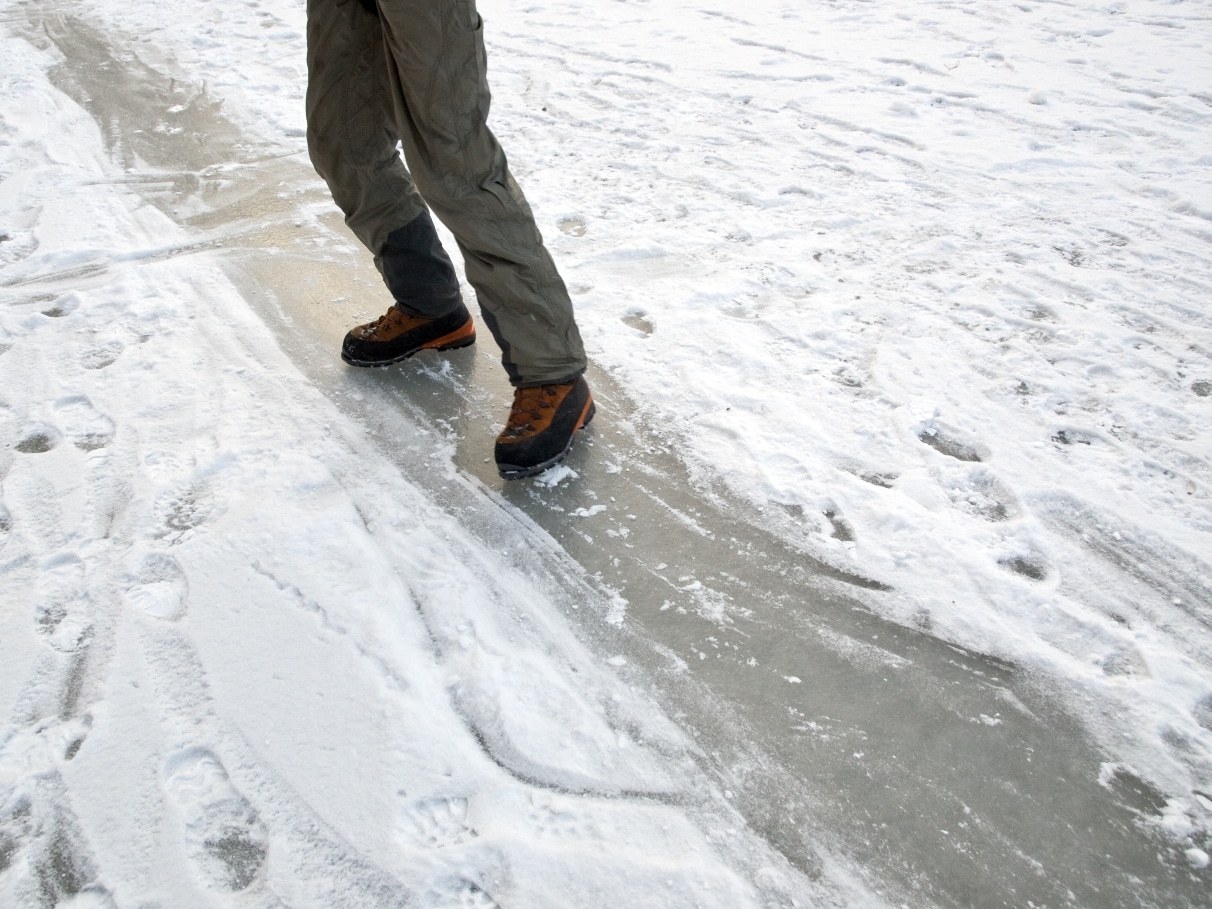 Image of a man in boots sliding on ice in Minnesota.