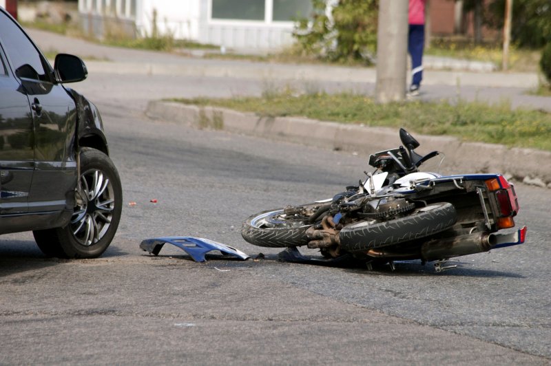Image of an accident scene between a sedan and a motorcycle.