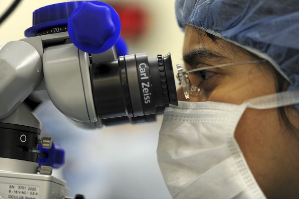 A doctor researching a medical device in a microscope, hoping to prevent malpractice that could cause a personal injury claim.