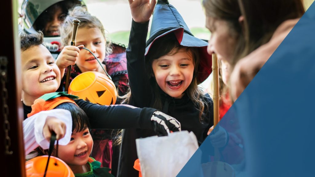 A group of trick-or-treaters getting candy from a local neighbor.