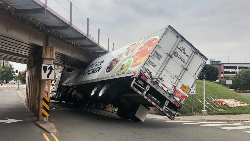 An image of a truck stuck underneath a bridge for an articled titled Why Truck Accidents are on the Rise for a blog by Nelson Personal Injury