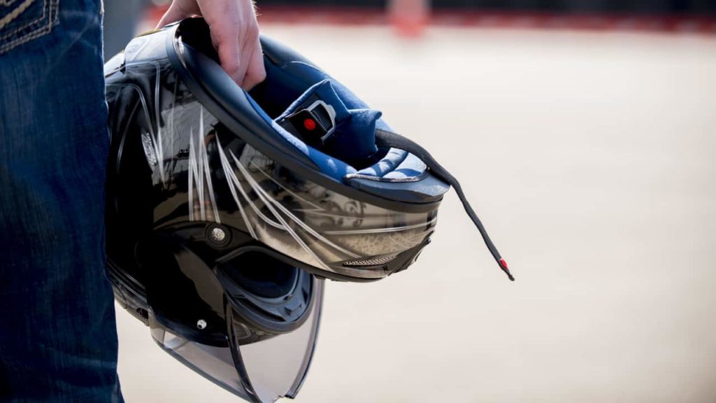 A man holds a motorcycle helmet.