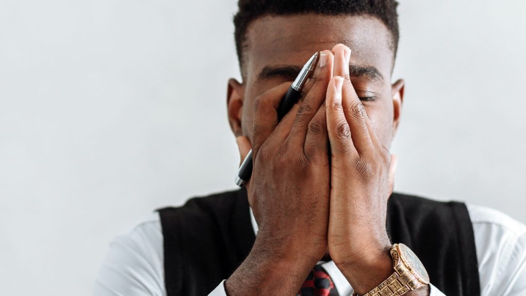 A man holds his hands to his face as if to calm himself of stress and anxiety due to his court case.