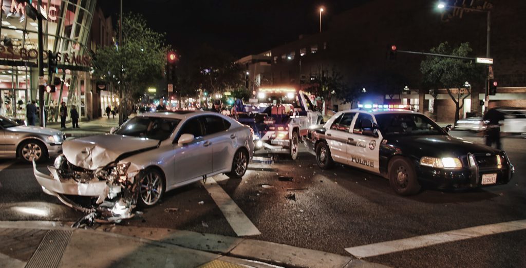 A car in the middle of the road with its front bumper crushed.